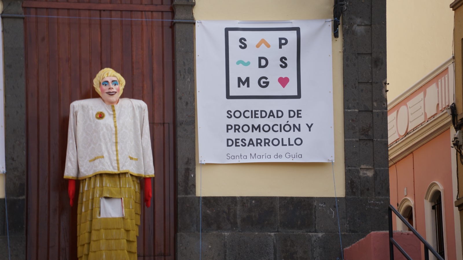 Papagüevo en representación a Xayo acompañado del cartel de la Sociedad de Promoción y Desarollo de Santa María de Guía